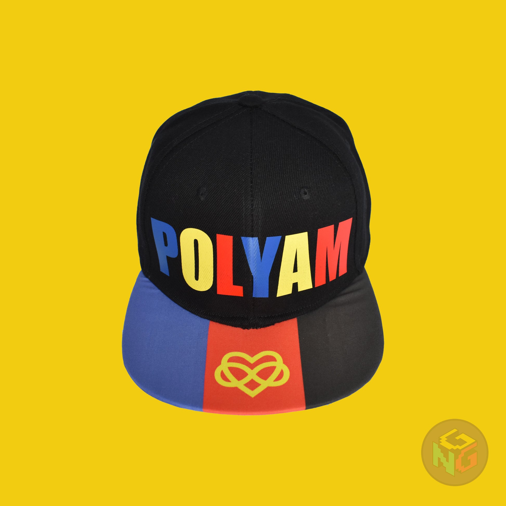Black flat bill snapback hat. The brim has the polyamory pride flag with the heart infinity symbol on both sides and the front of the hat has the word “POLYAM” in red, yellow, and blue letters. Front top view