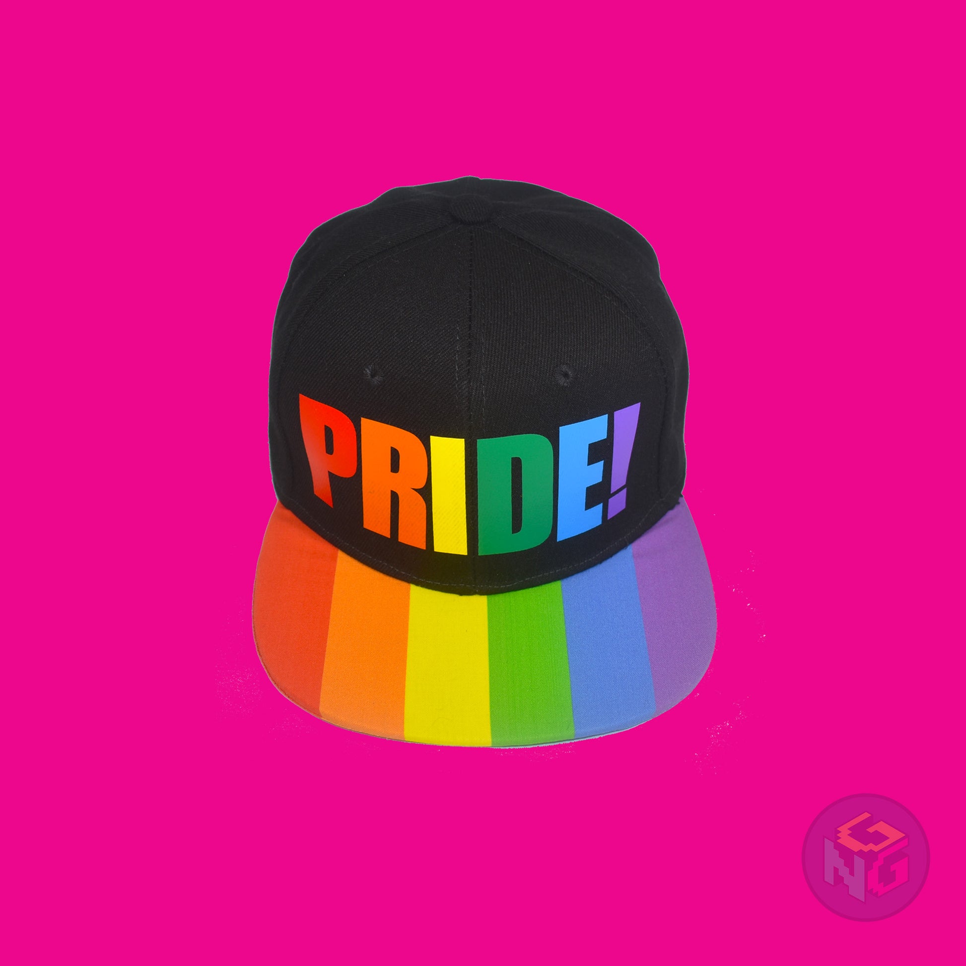 Black flat bill snapback hat. The brim has the rainbow pride flag on both sides and the front of the hat has the word “PRIDE!” in rainbow letters. Front top view