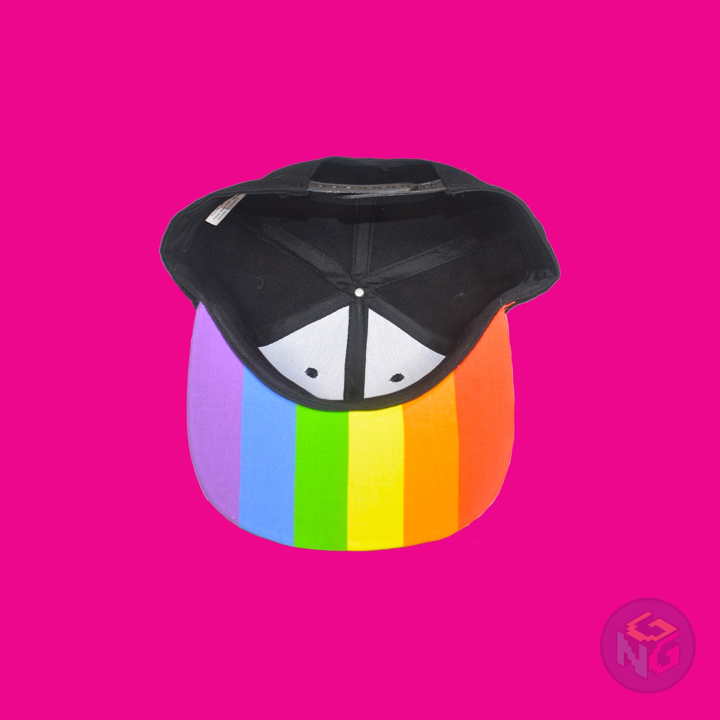 Black flat bill snapback hat. The brim has the rainbow pride flag on both sides and the front of the hat has the word “PRIDE!” in rainbow letters. Underside view