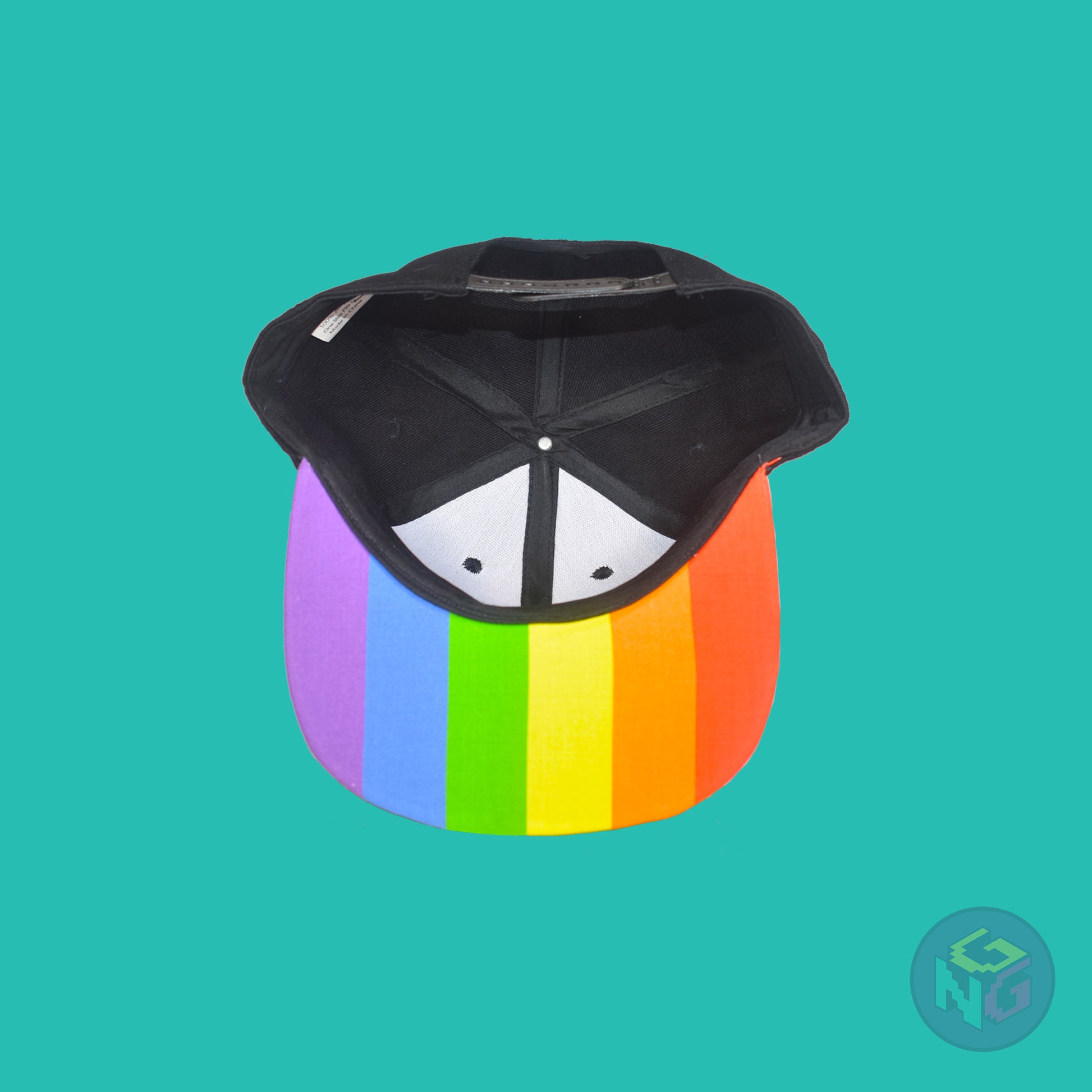 Black flat bill snapback hat. The brim has the rainbow pride flag on both sides and the front of the hat has the word “QUEER!” in rainbow letters. Underside view