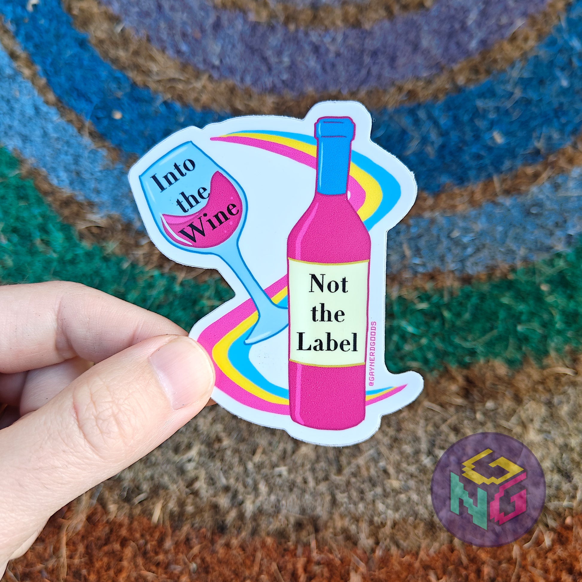 into the wine not the label pansexual pride vinyl sticker held in front of a rainbow welcome mat