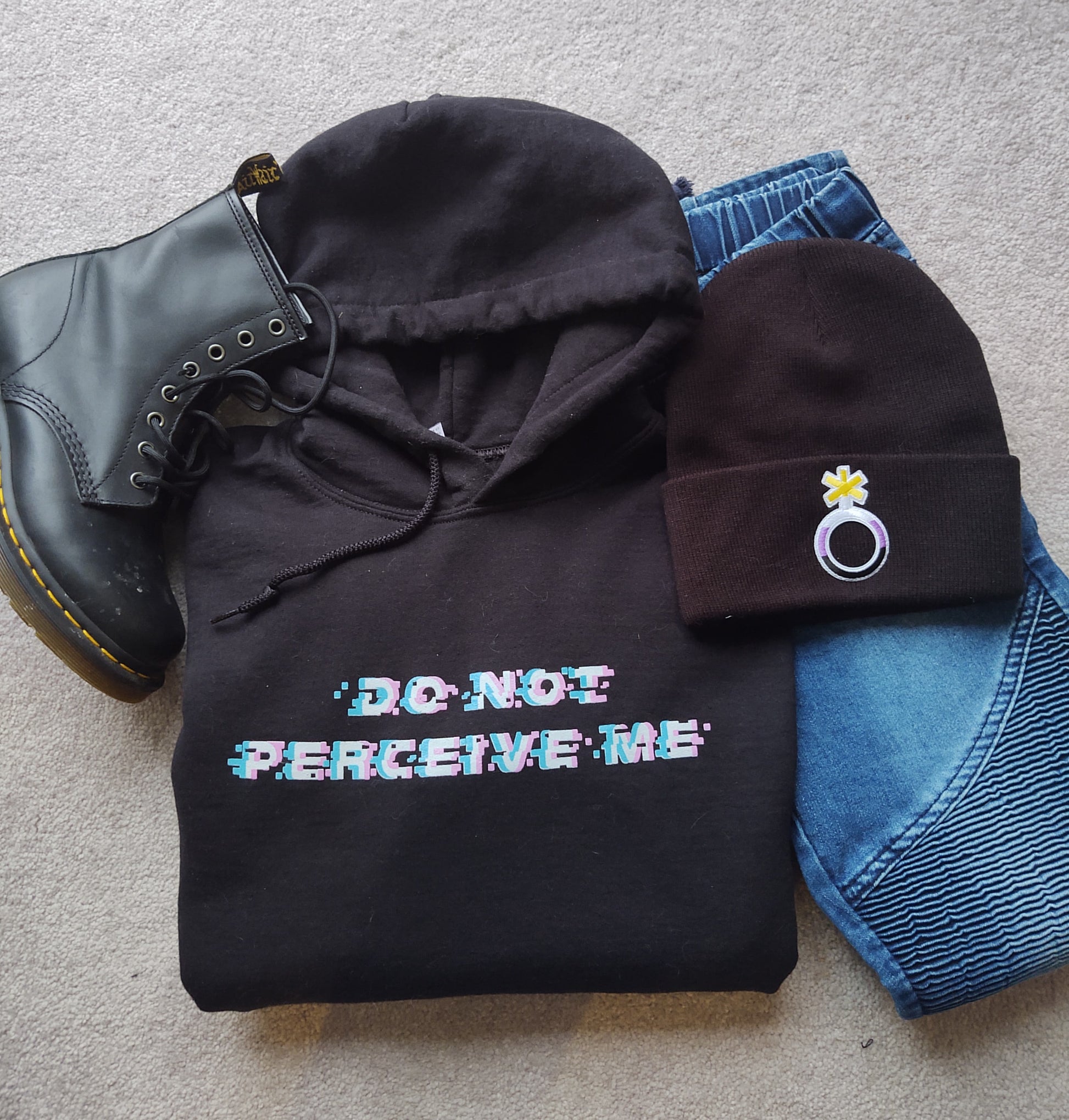 do not perceive me hoodie folded with doc martin, nonbinary beanie, and jeans