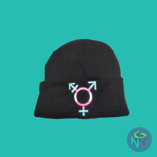 Black knit fabric beanie with the transgender symbol in blue, pink, and white on the front. It is laying flat on a mint green background