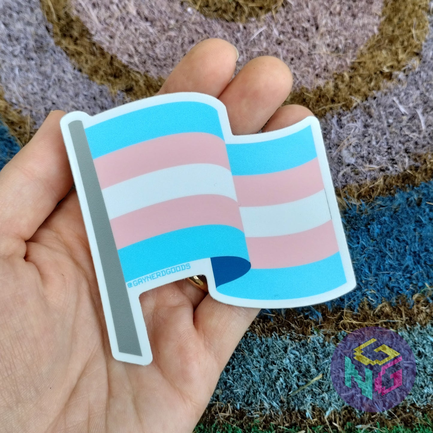 vinyl transgender flag sticker held in hand against rainbow welcome mat
