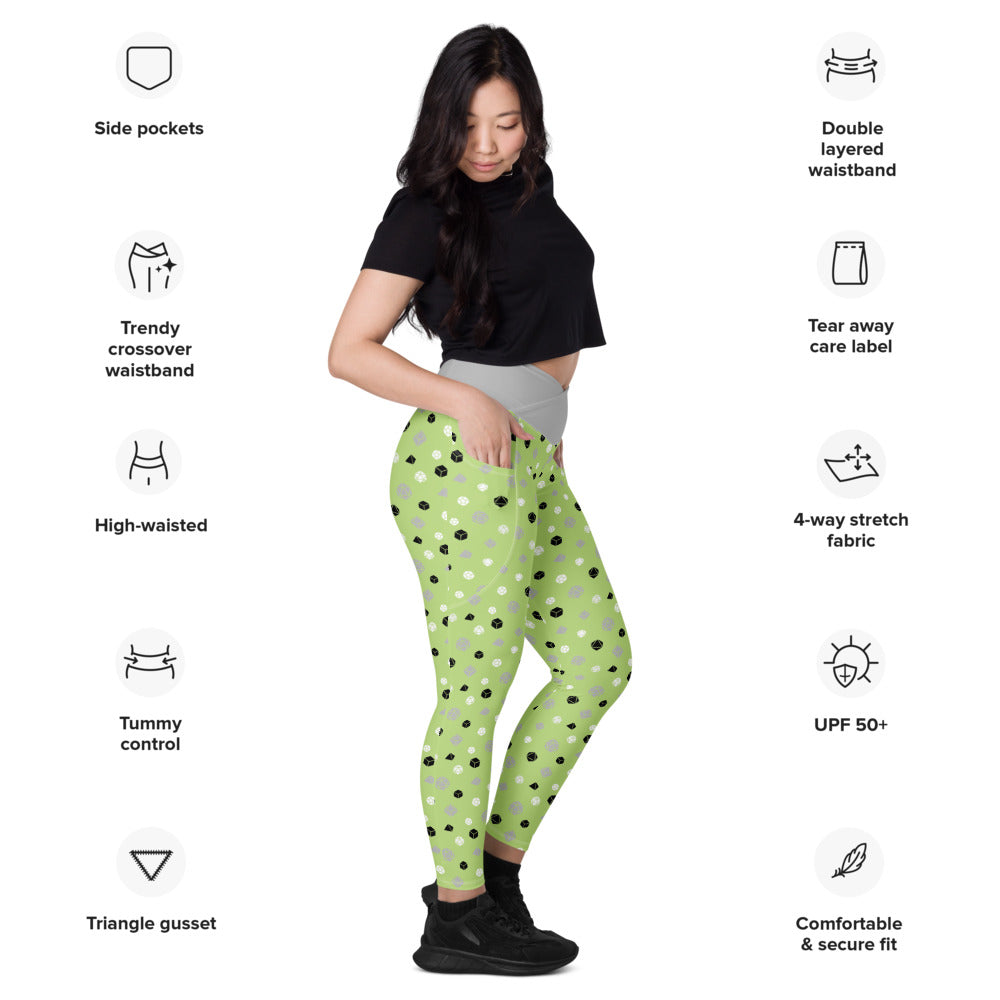Light-skinned dark-haired female-presenting model wearing the agender dice leggings. she is facing right and has a hand in the pocket. she is surrounded by product specs: "side pockets, trendy crossover waistband, high-waisted, tummy control, triangle gusset, double layered waistband, tear away care label, 4-way stretch fabric, UPF 50+, comfortable & secure fit"