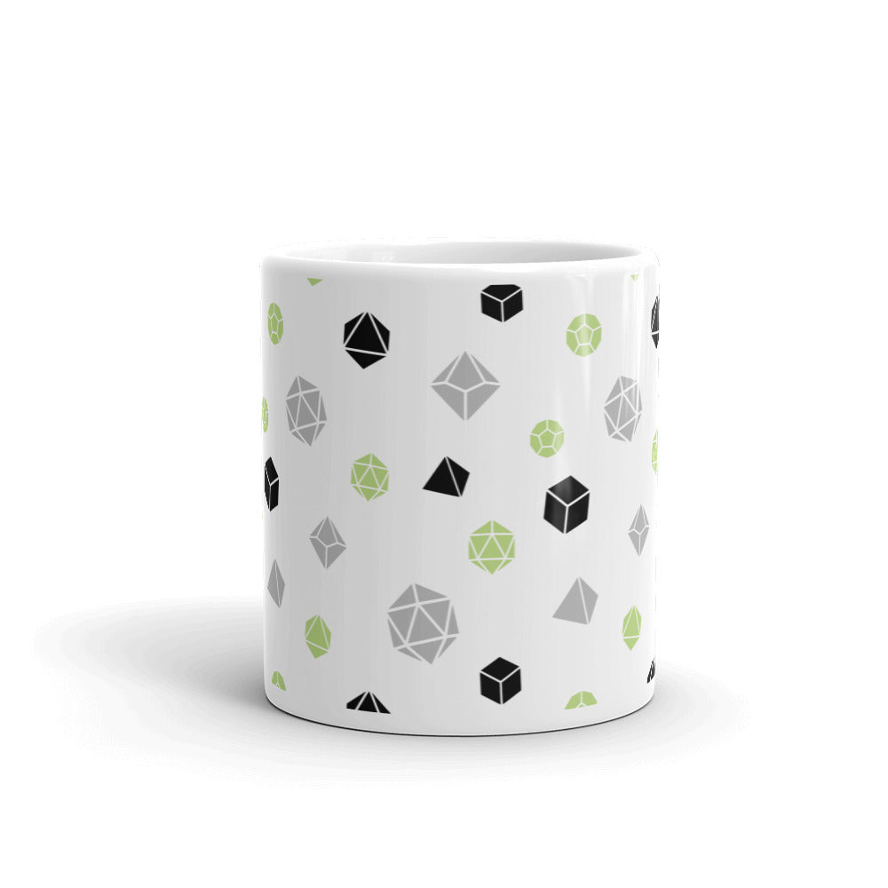 white mug on a white background with handle facing back. It has an all-over print of polyhedral d&d dice in the agender colors of green, grey, and black