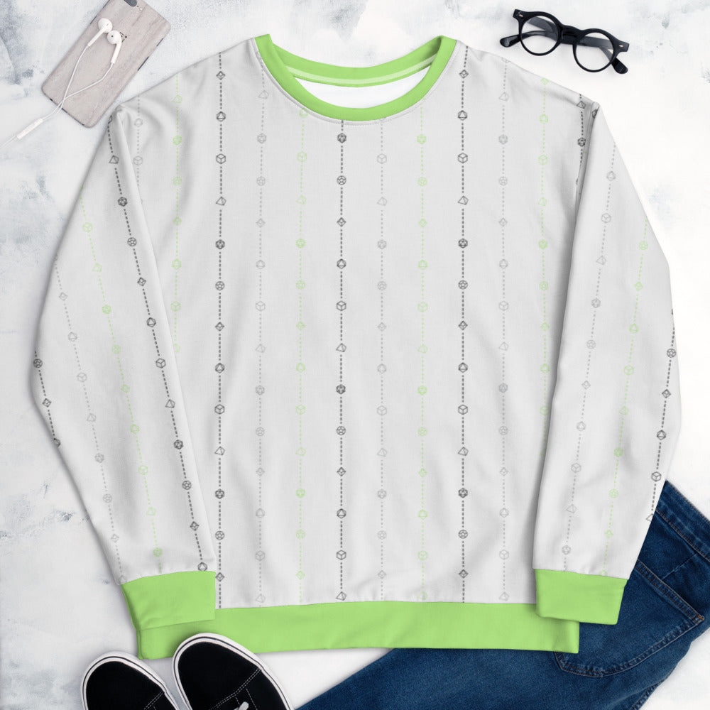 The agender pride sweater laying flat, surrounded by clothes, a phone, and glasses. the sweater is white and has stripes of dashed lines and polyhedral dnd dice in green, grey, and black. The cuffs, collar, and waistband are green