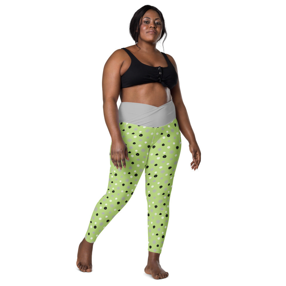 front view of dark-skinned female-presenting plus size model wearing the agender dice leggings and a black sports bra. This view shows off the grey crossover high-rise waistband