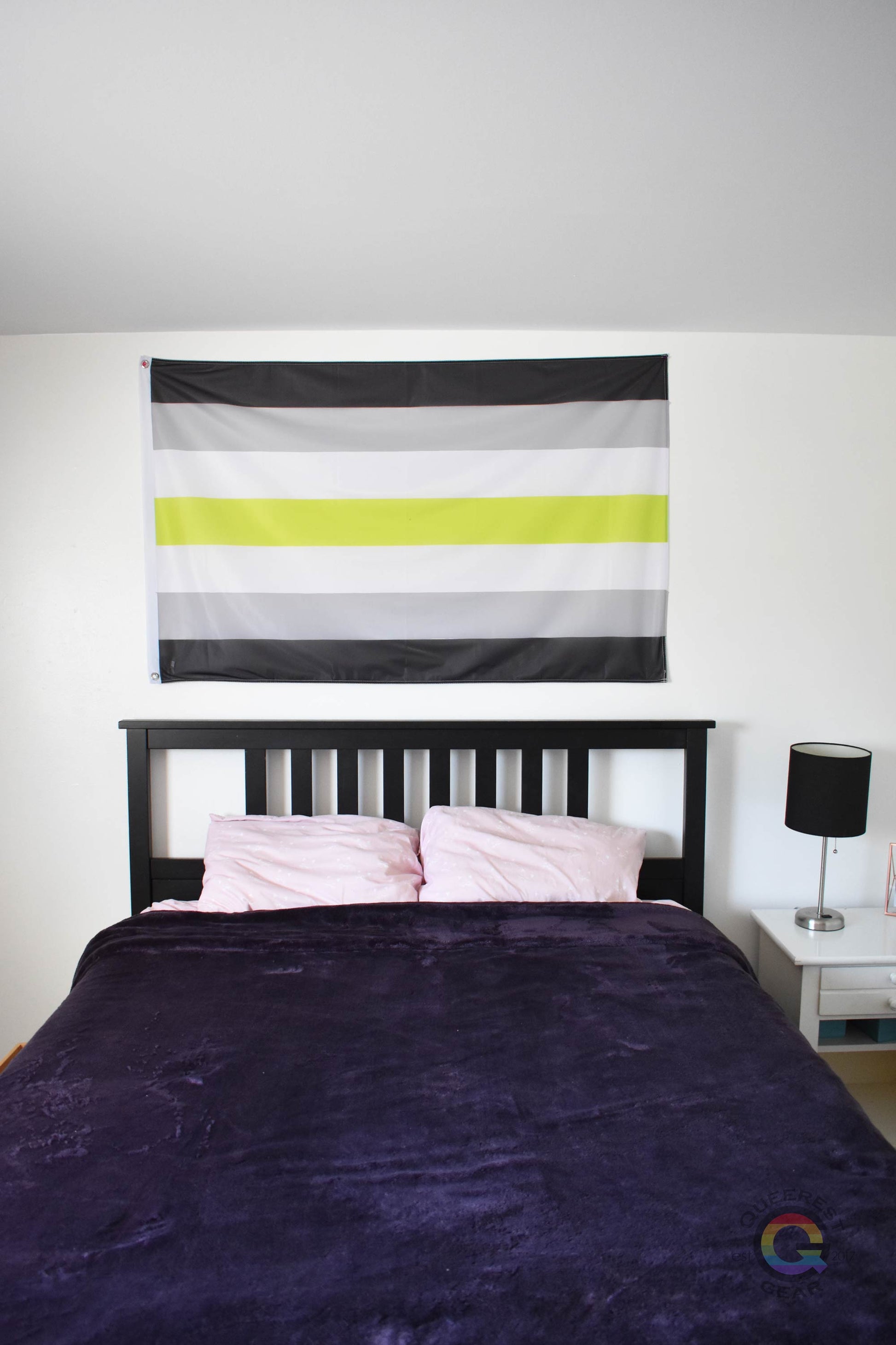3’x5’ agender pride flag hanging horizontally on the wall of a bedroom centered above a bed with a purple blanket