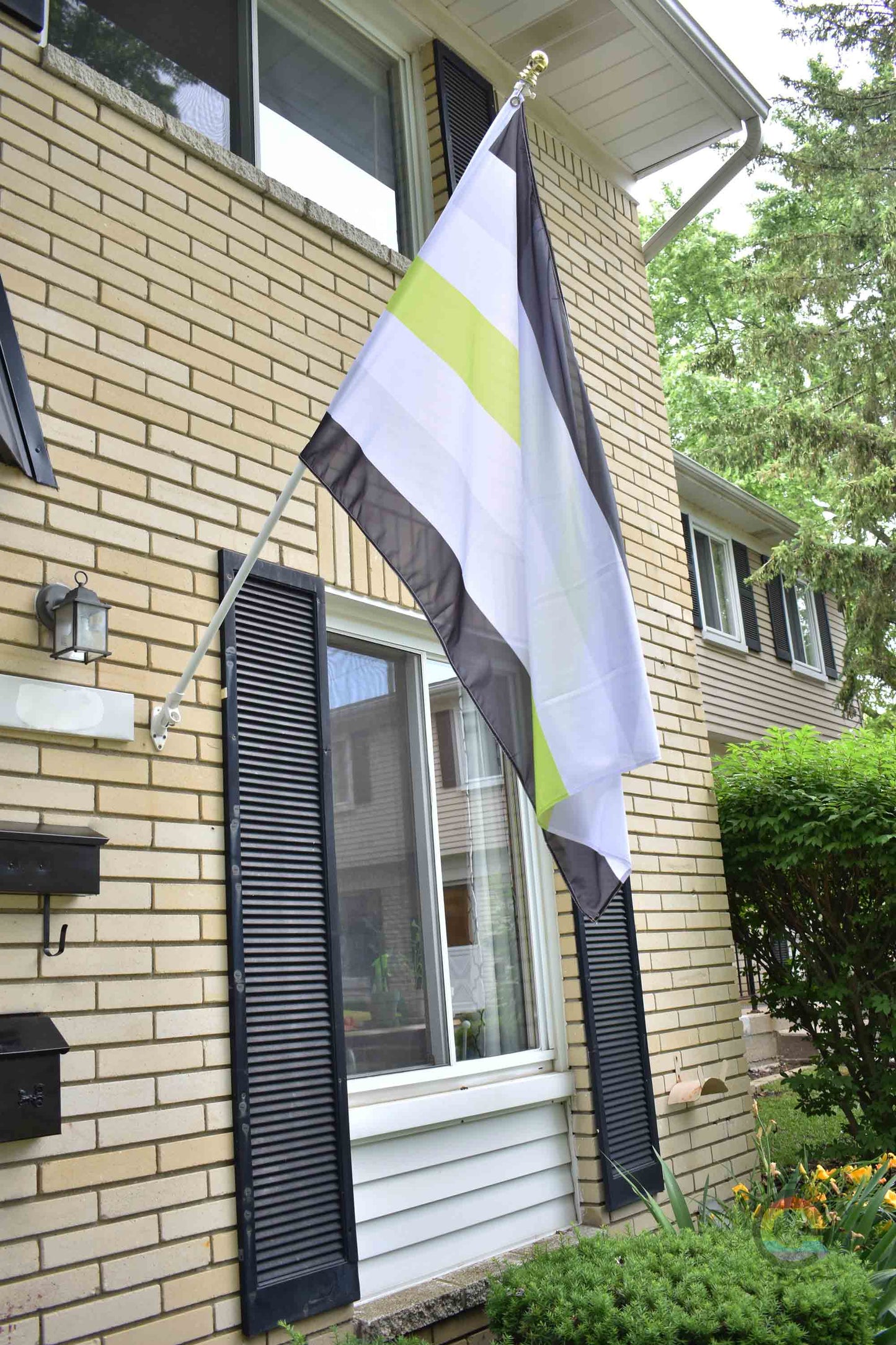 3’x5’ agender pride flag hanging from a flagpole on the outside of a light brick house with dark shutters