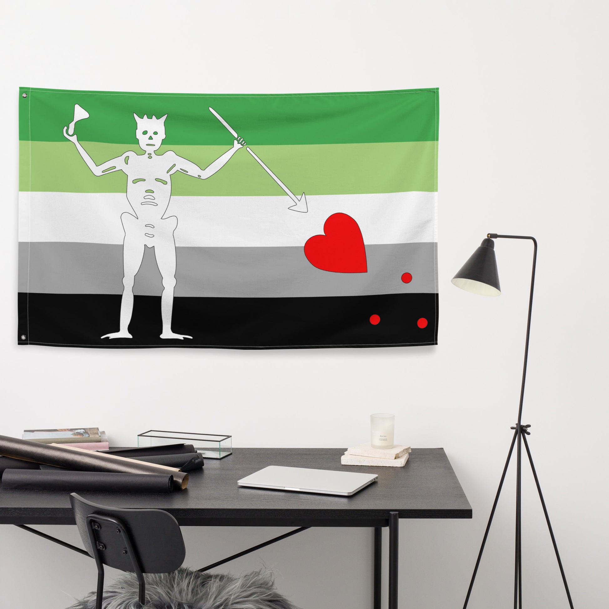 the aromantic flag with green, white, grey, and black stripes and blackbeard's symbol hanging on the wall above a small office desk