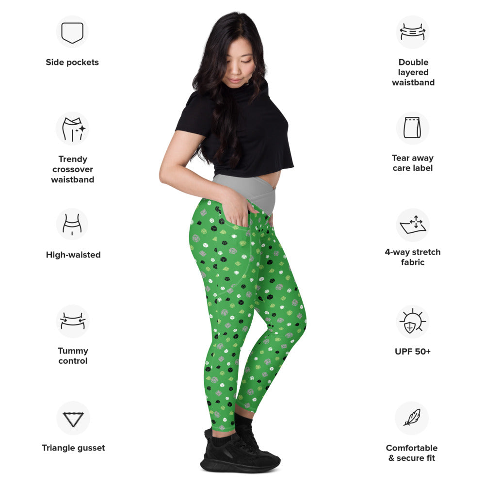 Light-skinned dark-haired female-presenting model wearing the aromantic dice leggings. she is facing right and has a hand in the pocket. she is surrounded by product specs: "side pockets, trendy crossover waistband, high-waisted, tummy control, triangle gusset, double layered waistband, tear away care label, 4-way stretch fabric, UPF 50+, comfortable & secure fit"