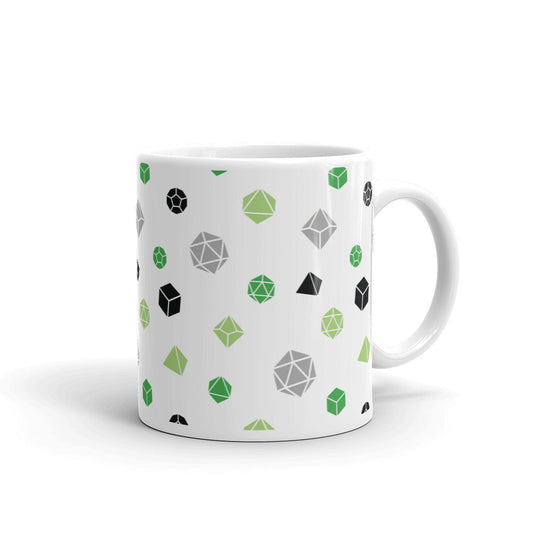white mug on a white background with handle facing right. It has an all-over print of polyhedral d&d dice in the aromantic colors of greens, grey, and black
