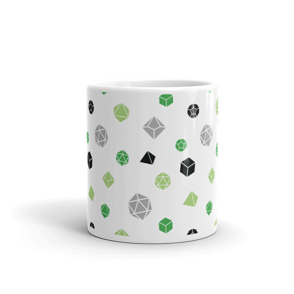 white mug on a white background with handle facing back. It has an all-over print of polyhedral d&d dice in the aromantic colors of greens, grey, and black