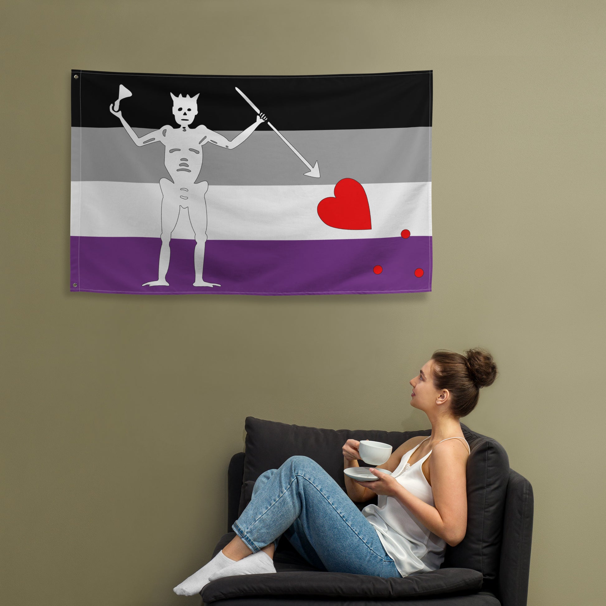 the asexual blackbeard pride flag hanging on a khaki wall above a person laying in a chair drinking tea and looking up