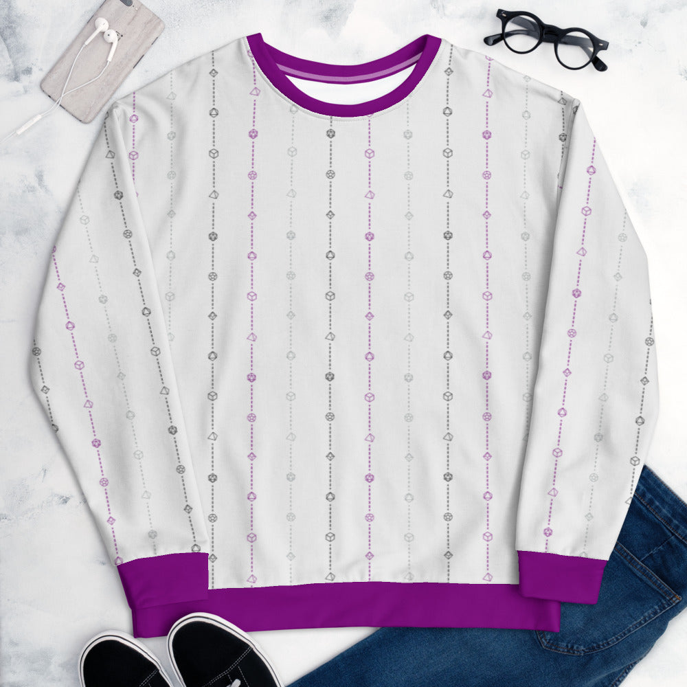 The asexual pride sweater laying flat, surrounded by clothes, a phone, and glasses. the sweater is white and has stripes of dashed lines and polyhedral dnd dice in purple, grey, and black. The cuffs, collar, and waistband are purple