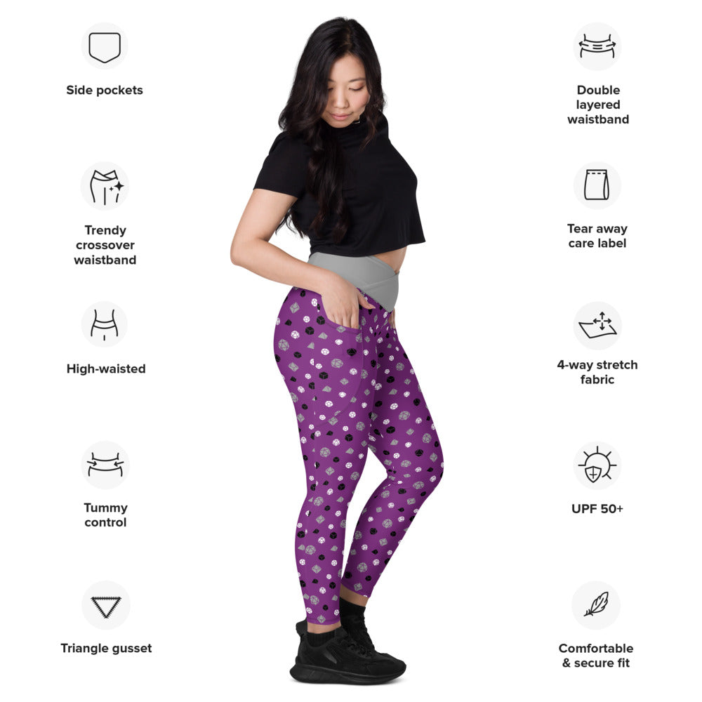 Light-skinned dark-haired female-presenting model wearing asexual dice leggings. she is facing right and has a hand in the pocket. she is surrounded by product specs: "side pockets, trendy crossover waistband, high-waisted, tummy control, triangle gusset, double layered waistband, tear away care label, 4-way stretch fabric, UPF 50+, comfortable & secure fit
