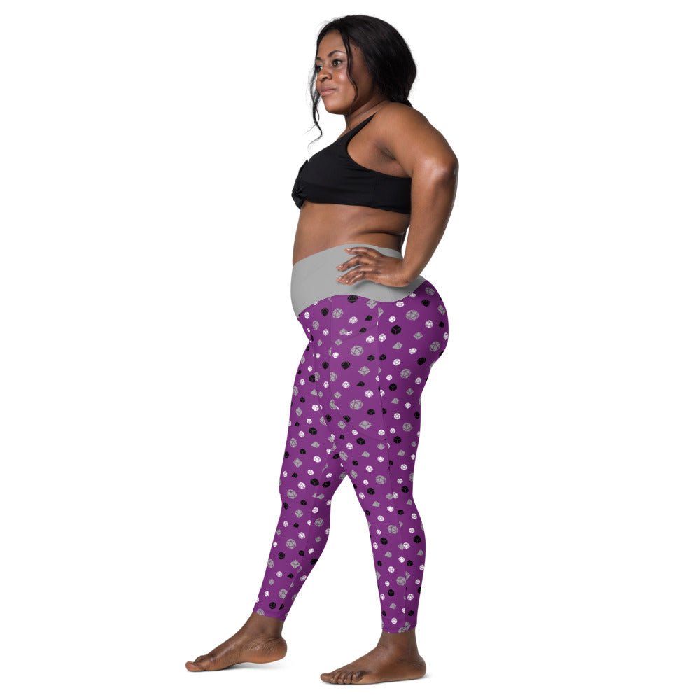 Left side view of dark-skinned female-presenting model wearing the asexual dice leggings and black sports bra. She is facing left with her left hand on her hip and right leg forward