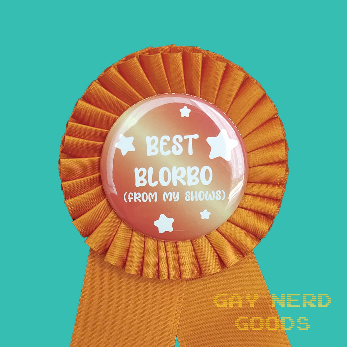 detail shot of central button of the best blorbo award ribbon. The text says "best blorbo (from my shows)" in white surrounded by stars. They're on an orange and yellow gradient button surrounded by orange satin ribbon