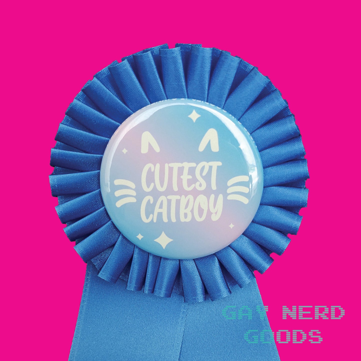 detail close up of the "cutest catboy" award ribbon. The text is white and surrounded by white cat ears and whiskers and white sparkles. The background is pink and blue gradient. The satin ribbon is dark blue