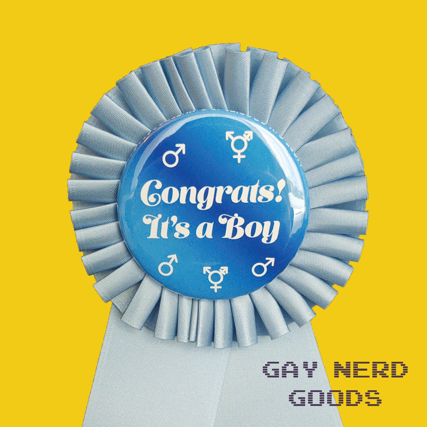 close up detail of the "congrats! it's a boy" award ribbon. the text is white surrounded by white trans and male symbols. The background of the design is dark and medium blue gradient and the ribbon is light blue.