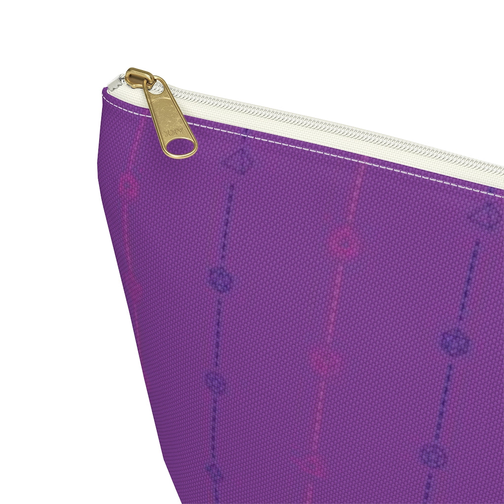 the large bisexual dice t-bottom pouch zoomed in on the corner on a white background. it's purple with pink and blue stripes of dashed lines and polyhedral dice and a gold zipper pull