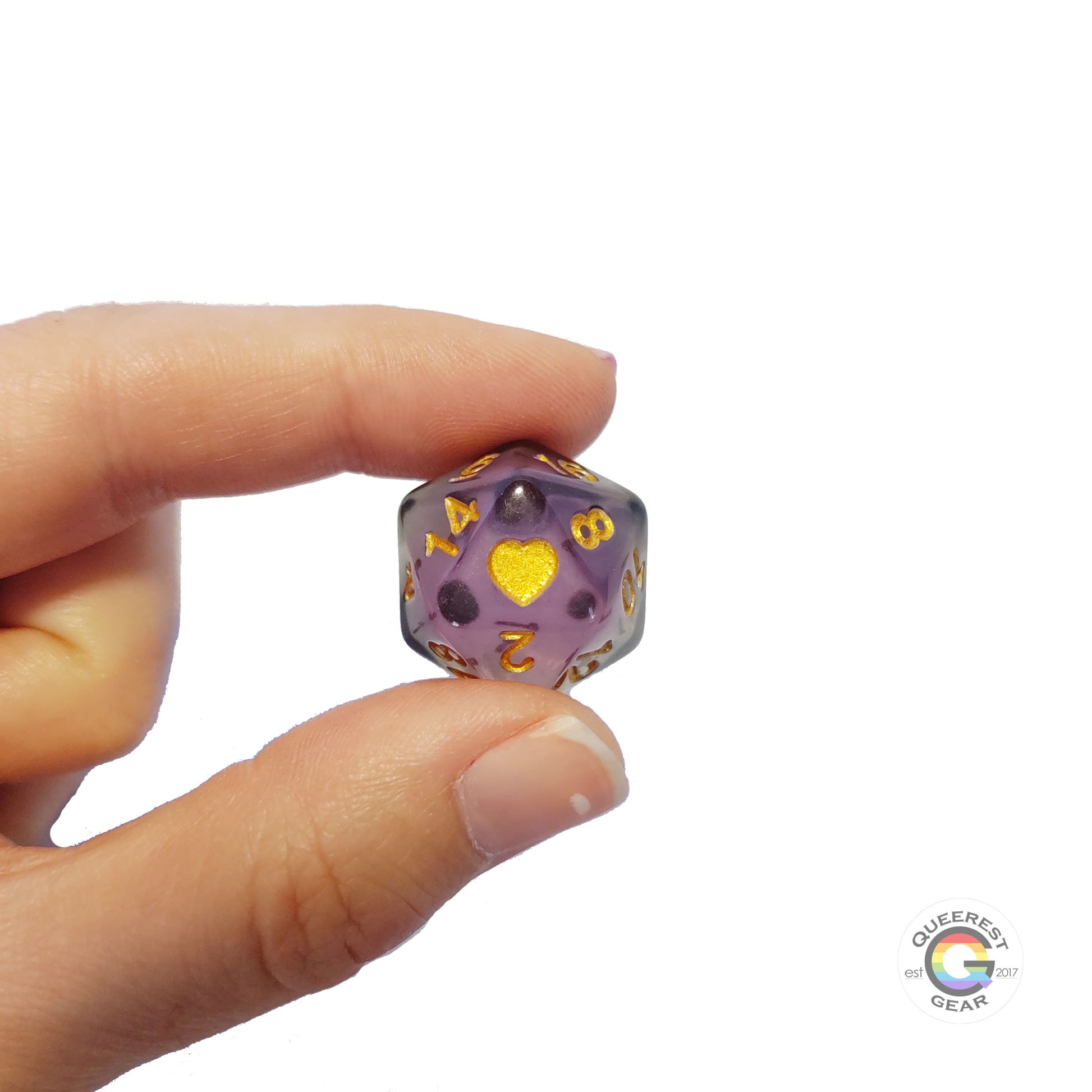 A hand holding up the asexual d20 to show off the color, heart, and transparency