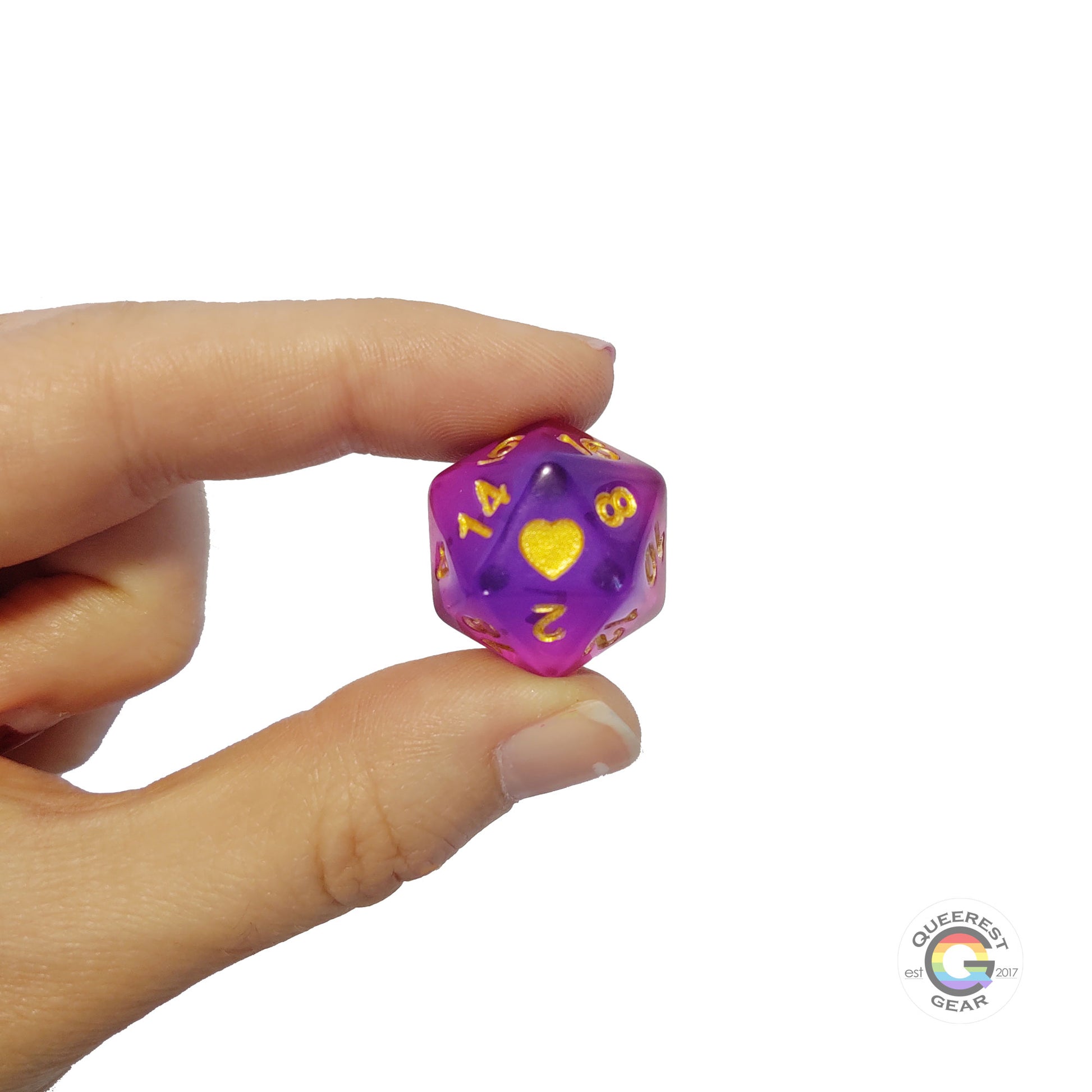 A hand holding up the bisexual d20 to show off the color, heart, and transparency