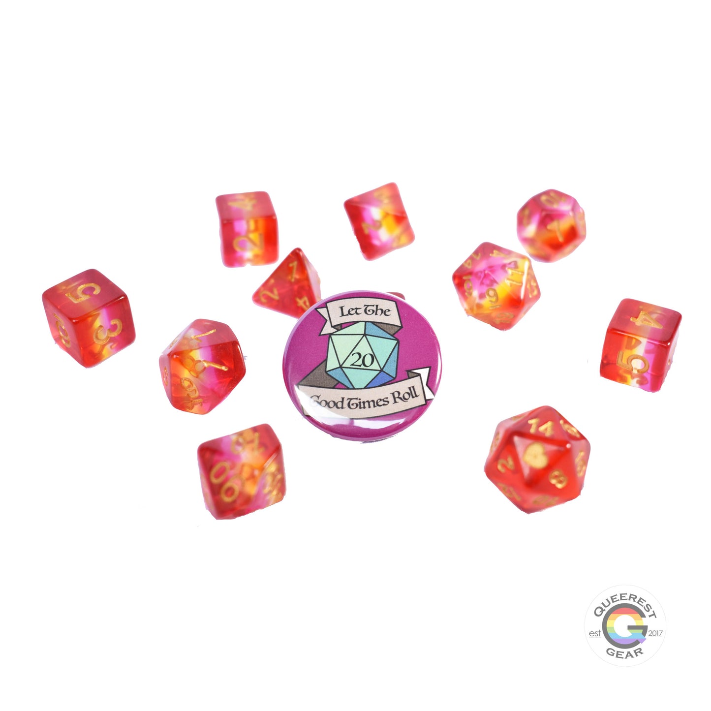 11 piece set of polyhedral dice scattered on a white background. They are transparent and colored in the stripes of the lesbian flag with gold ink. There is the freebie “let the good times roll” pinback button among them.