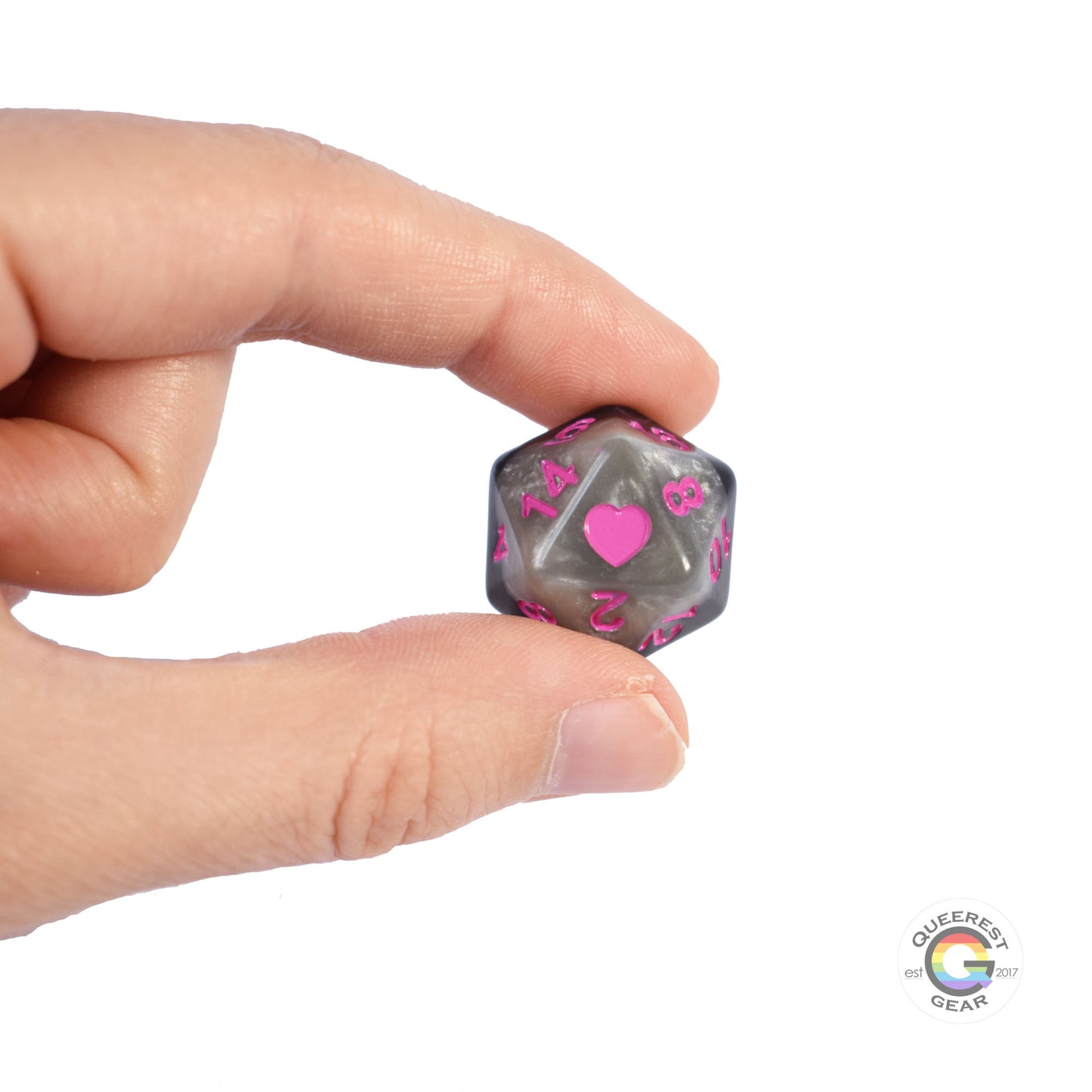 A hand holding up the demisexual d20 to show off the heart, color, and transparency