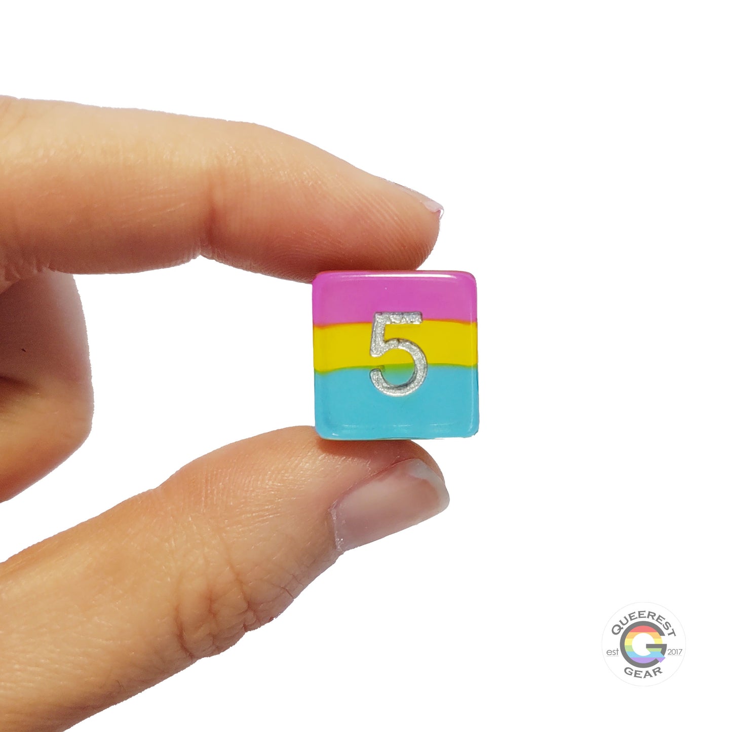 A hand holding up the pansexual d6 to show off the color and transparency