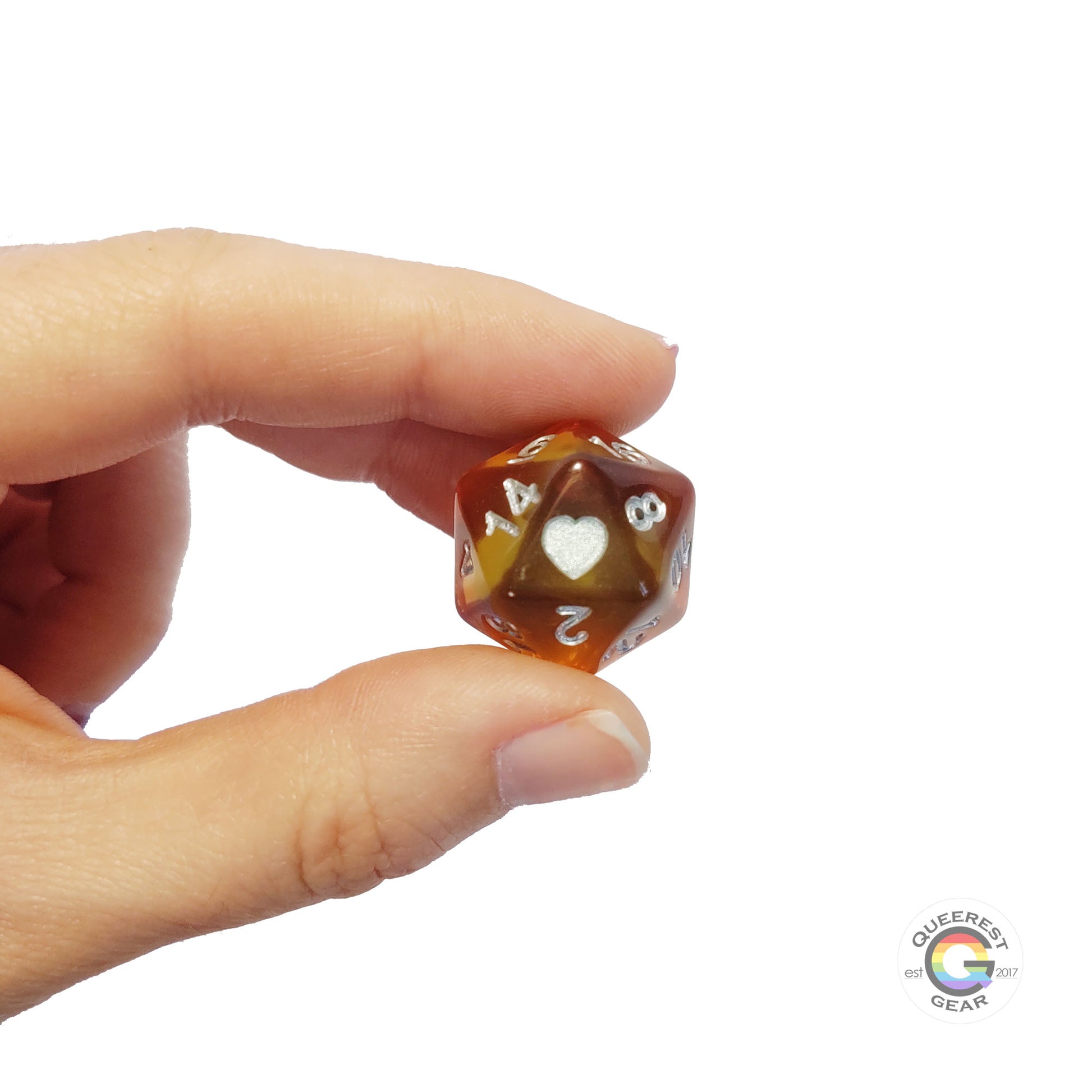 A hand holding up the pansexual d20 to show off the color, heart, and transparency