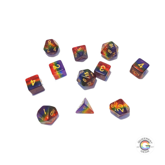 11 piece set of polyhedral dice scattered on a white background. They are transparent and colored in the stripes of the rainbow flag with gold ink.
