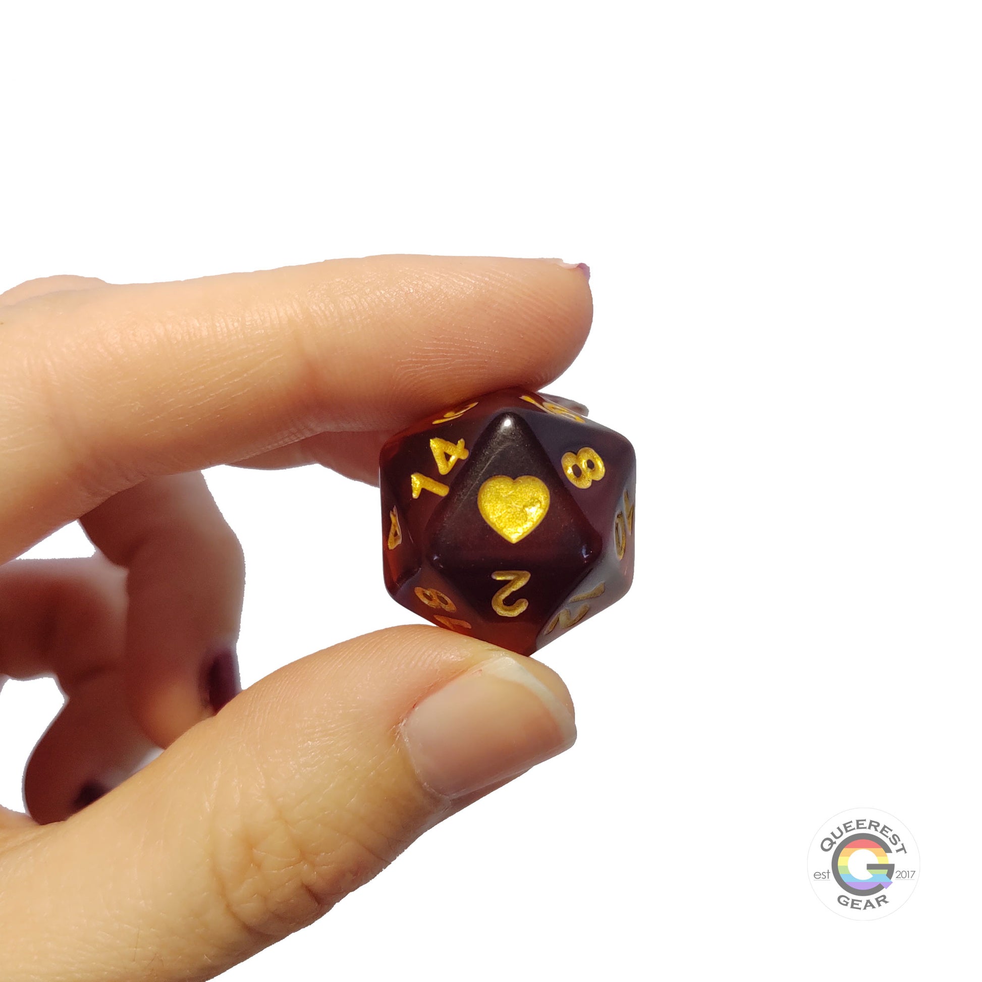  A hand holding up the rainbow d20 to show off the color, heart, and transparency
