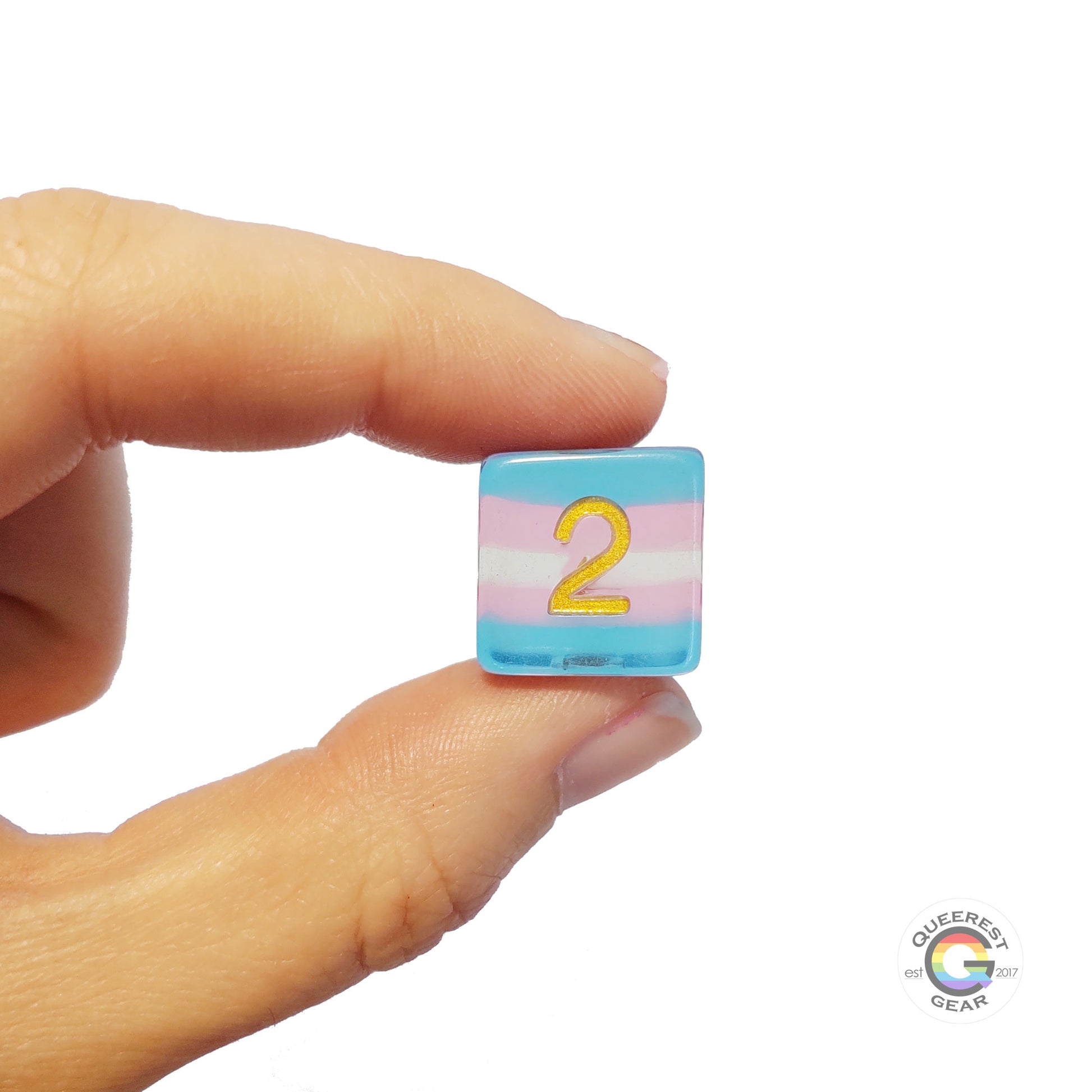 A hand holding up the transgender d6 to show off the color and transparency