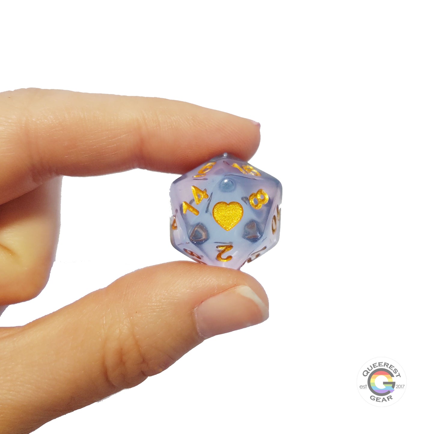 A hand holding up the transgender d20 to show off the color, heart, and transparency