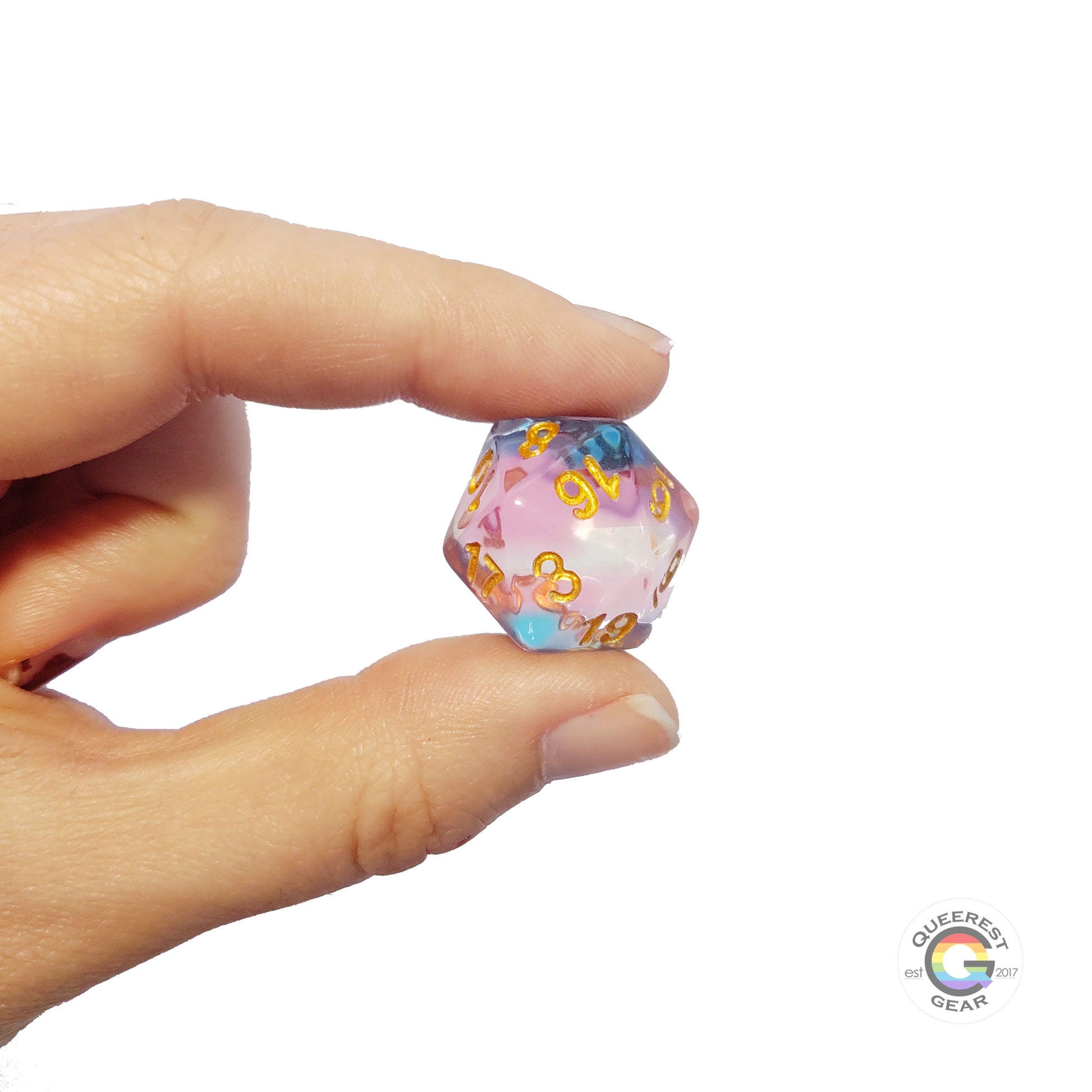 A hand holding up the transgender d20 to show off the color and transparency