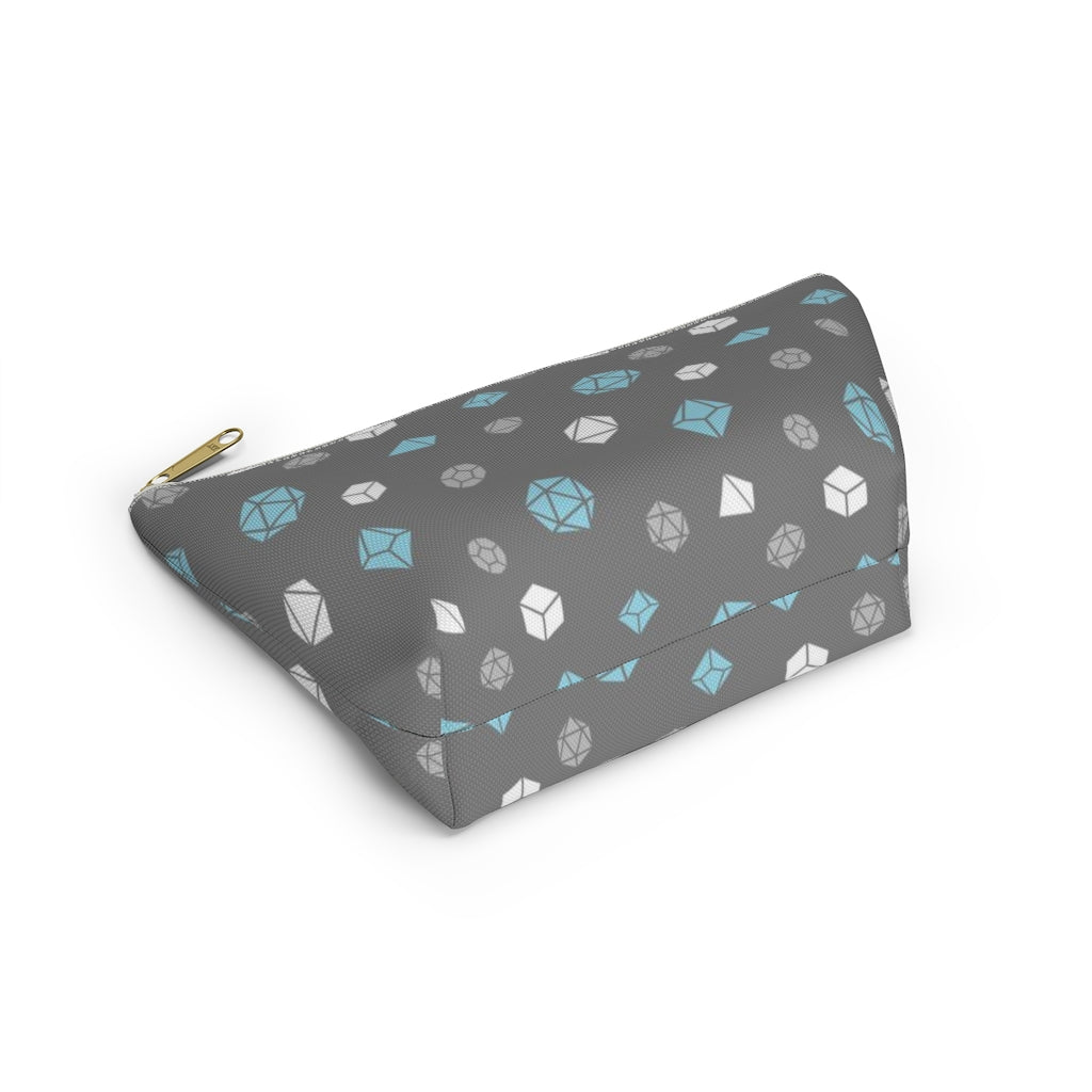 the small demiboy dice t-bottom pouch in bottom view on a white background. it's dark grey with light grey, white, and blue polyhedral dice and a gold zipper pull