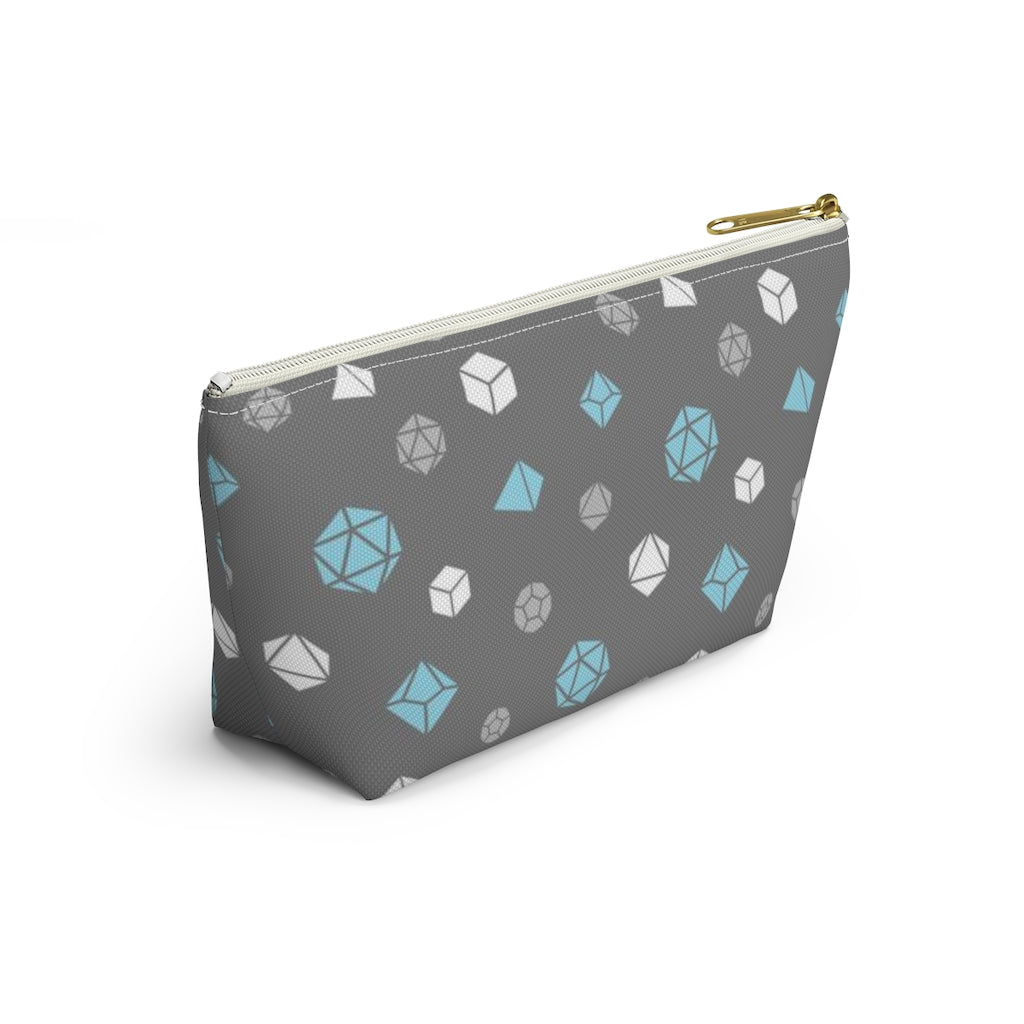 the small demiboy dice t-bottom pouch in side view on a white background. it's dark grey with light grey, white, and blue polyhedral dice and a gold zipper pull