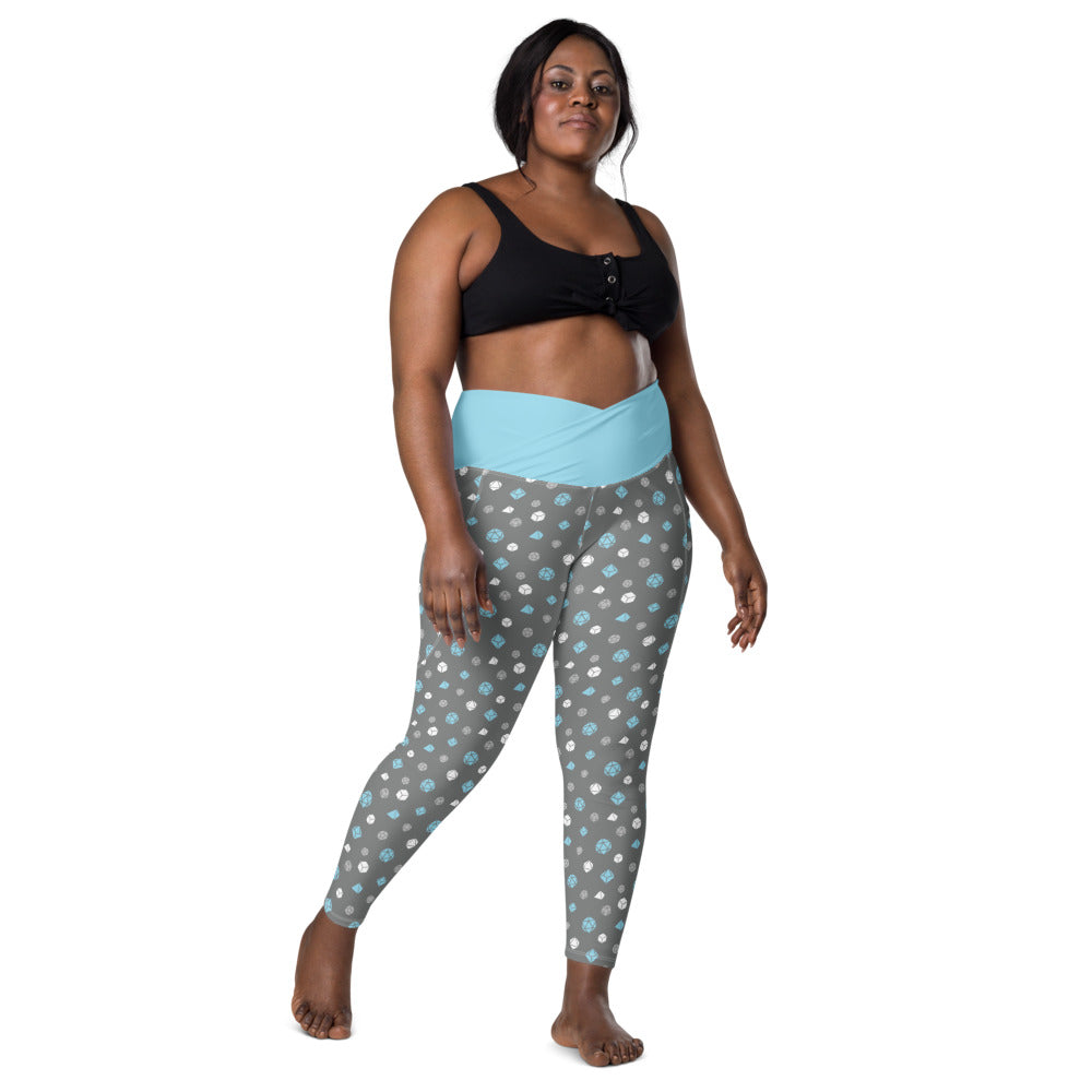 front view of dark-skinned female-presenting plus size model wearing the demiboy dice leggings and a black sports bra. This view shows off the blue crossover high-rise waistband