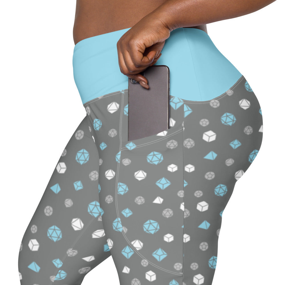 left side view of the demiboy dnd dice plus size leggings. the dark-skinned female-presenting model is sliding her phone into one of the side pockets