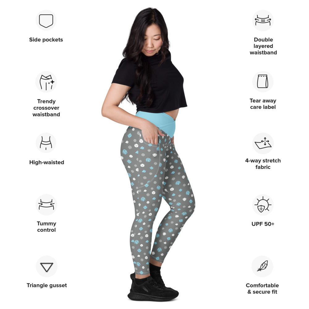 Light-skinned dark-haired female-presenting model wearing the demiboy dice leggings. she is facing right and has a hand in the pocket. she is surrounded by product specs: "side pockets, trendy crossover waistband, high-waisted, tummy control, triangle gusset, double layered waistband, tear away care label, 4-way stretch fabric, UPF 50+, comfortable & secure fit"