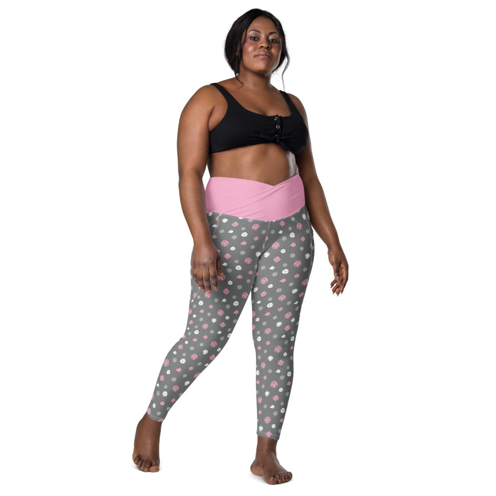 front view of dark-skinned female-presenting plus size model wearing the demigirl dice leggings and a black sports bra. This view shows off the pink crossover high-rise waistband