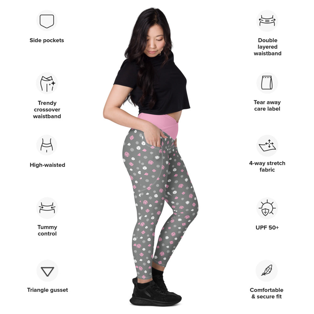 Light-skinned dark-haired female-presenting model wearing the demigirl dice leggings. she is facing right and has a hand in the pocket. she is surrounded by product specs: "side pockets, trendy crossover waistband, high-waisted, tummy control, triangle gusset, double layered waistband, tear away care label, 4-way stretch fabric, UPF 50+, comfortable & secure fit"