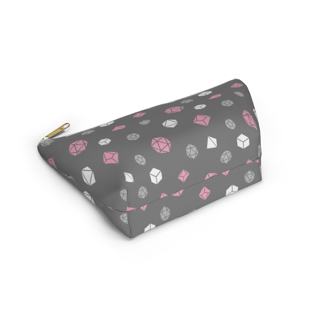 the small demigirl dice t-bottom pouch in bottom view on a white background. it's dark grey with light grey, white, and pink polyhedral dice and a gold zipper pull