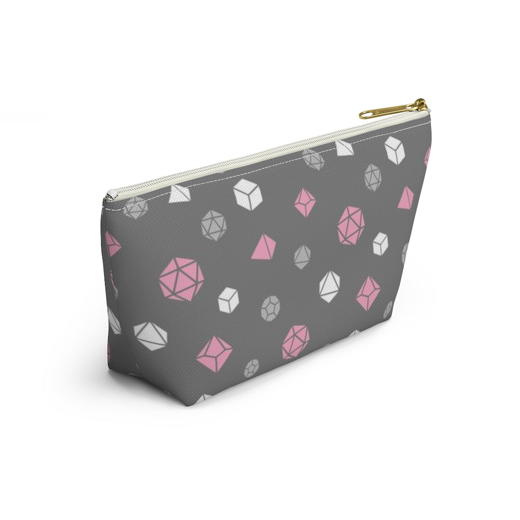 the small demigirl dice t-bottom pouch in side view on a white background. it's dark grey with light grey, white, and pink polyhedral dice and a gold zipper pull
