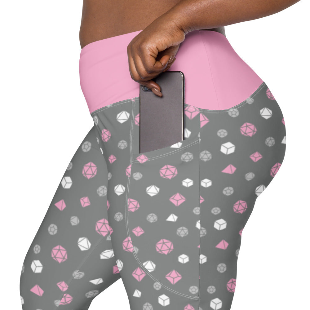 left side view of the demigirl dnd dice plus size leggings. the dark-skinned female-presenting model is sliding her phone into one of the side pockets