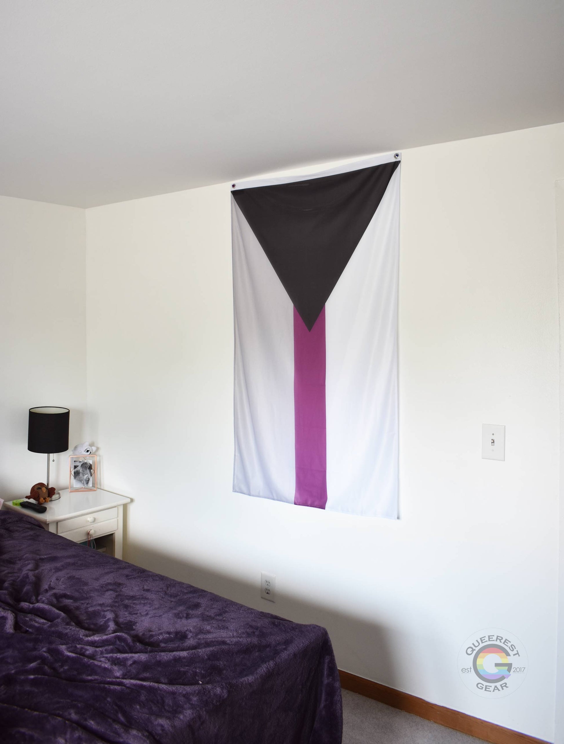  3’x5’ demisexual pride flag hanging vertically on the wall of a bedroom with a nightstand and a bed