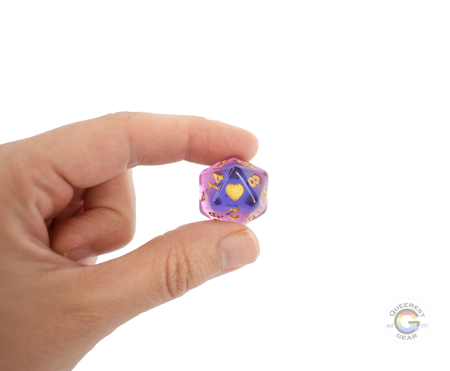 A hand holding up the genderfluid d20 to show off the color, heart, and transparency