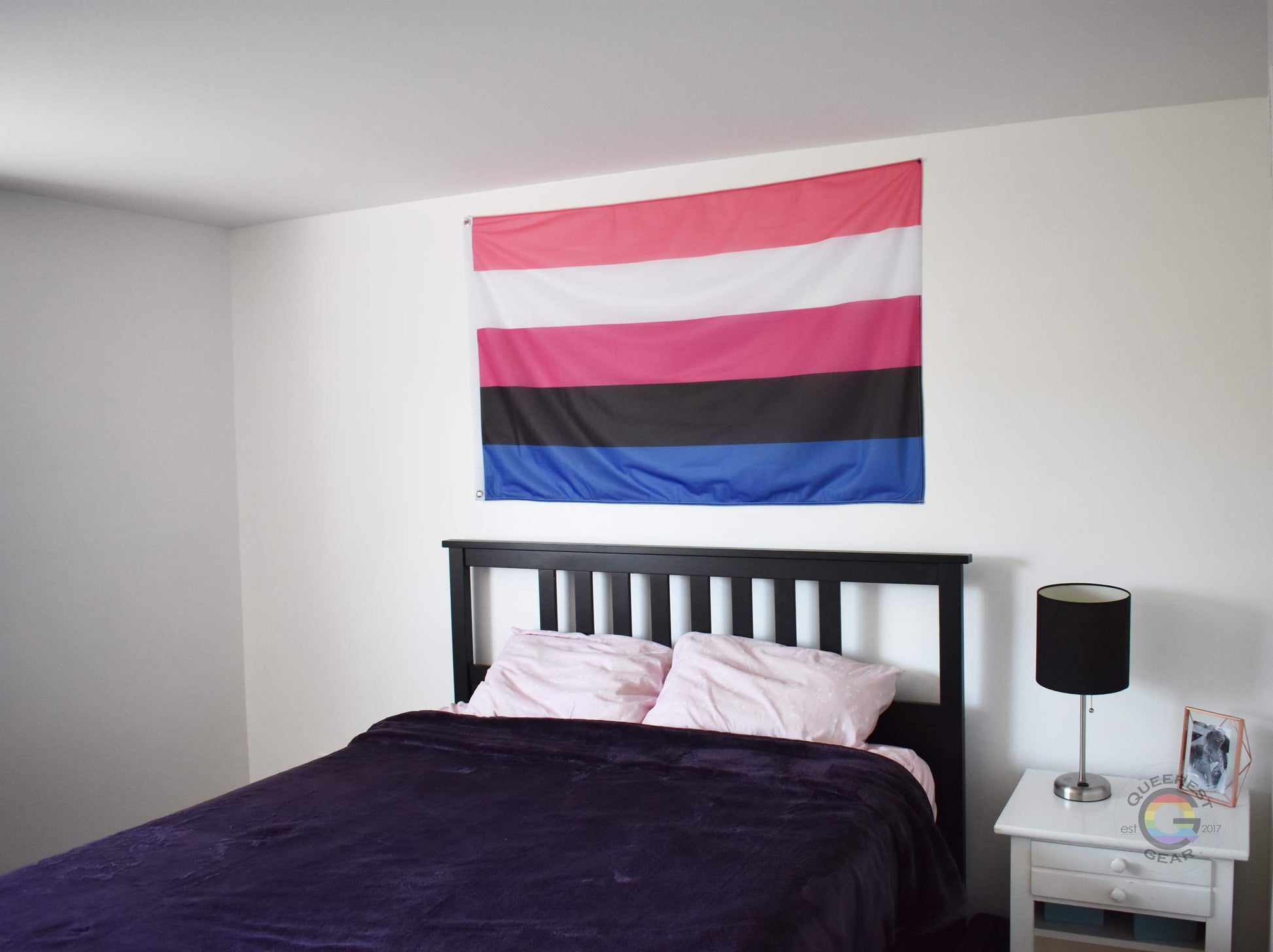 3’x5’ genderfluid pride flag hanging horizontally on the wall of a bedroom centered above a bed with a purple blanket